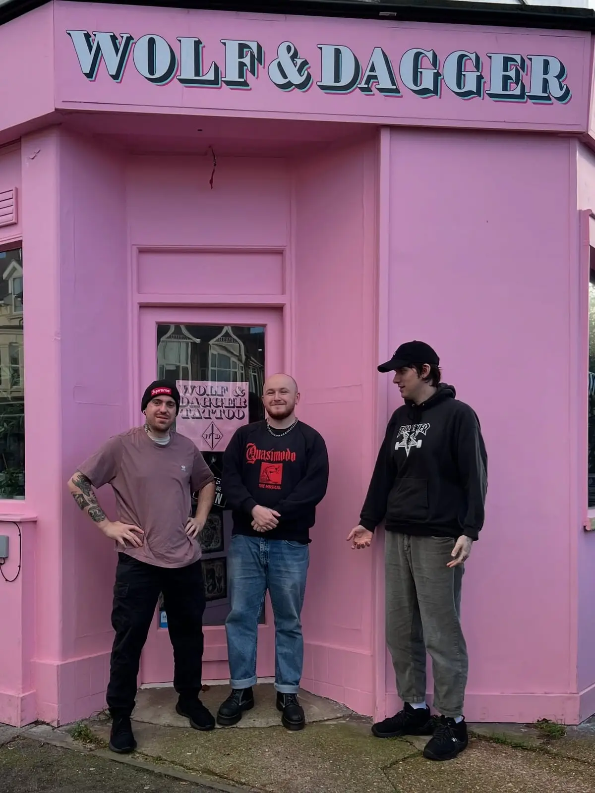 Pink shopfront of Wolf & Dagger Tattoo with the team outside in Hove