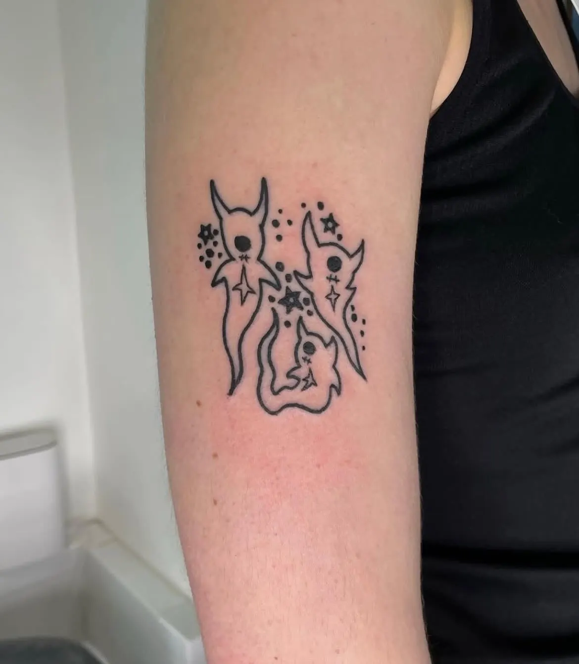 Small fine black figure tattoo on an upper arm Wolf & Dagger Tattoo Hove